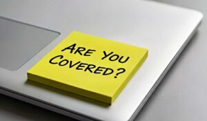 A close-up of a person reviewing car insurance documents and a driver's license at a home table.