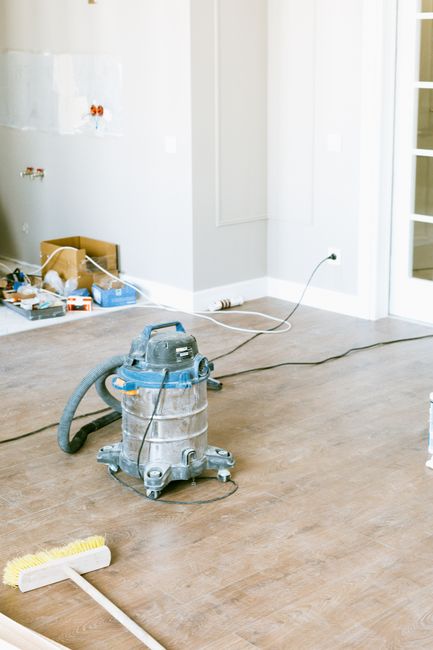 Homeowner examines water stains on a ceiling beside a bucket and damp flooring after a plumbing leak.